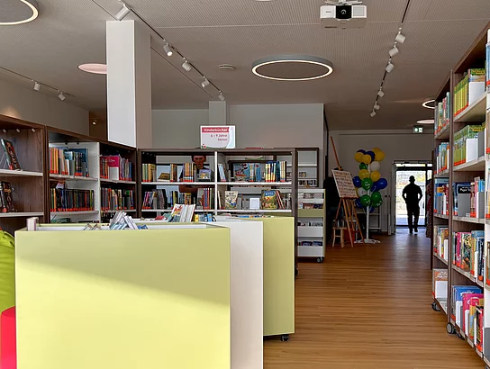 Blick durch den Innenraum mit Regalen, Sitzgelegenheiten und einem offenen Durchgang.