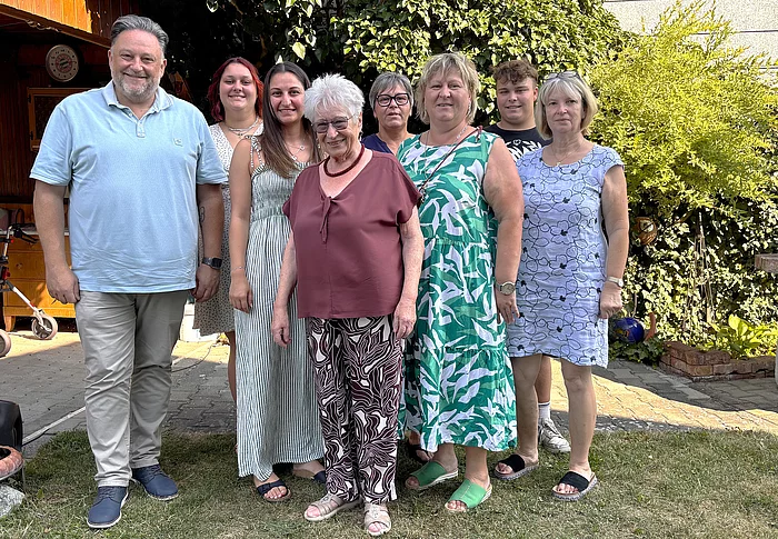 Bürgermeister Thomas Beer steht gemeinsam mit der Jubilarin Paula Schindler und mehreren Angehörigen im Garten ihres Hauses für ein Erinnerungsfoto anlässlich ihres 80. Geburtstags.