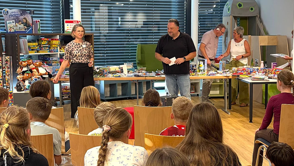 Zahlreiche Kinder sitzen in der neuen Stadtbücherei vor Büchereileiterin Corinna Höfler und Bürgermeister Thomas Beer, die gemeinsam durch die Preisverleihung des Sommerferien-Leseclubs führen.