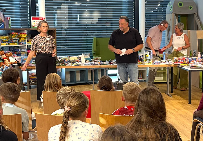 Zahlreiche Kinder sitzen in der neuen Stadtbücherei vor Büchereileiterin Corinna Höfler und Bürgermeister Thomas Beer, die gemeinsam durch die Preisverleihung des Sommerferien-Leseclubs führen.