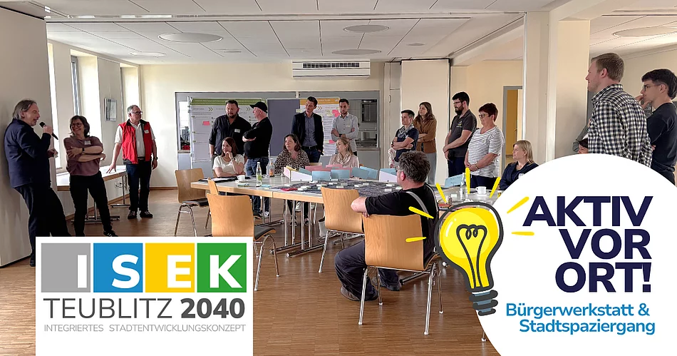 Mehrere Menschen sitzen und stehen um Tische in einem Seminarraum, während eine Person vorne spricht. Im Bild sind Logos und Schriftzüge zum Stadtentwicklungsprojekt „ISEK Teublitz 2040“ und „Aktiv vor Ort“ zu sehen.