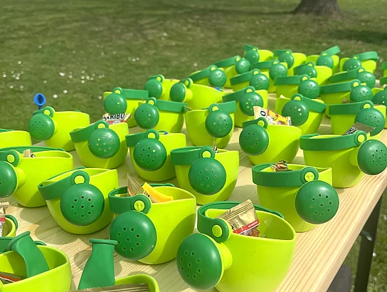Viele kleine grüne Gießkannen mit Süßigkeiten stehen auf einem Tisch und sind als Geschenke für die teilnehmenden Kinder vorbereitet.