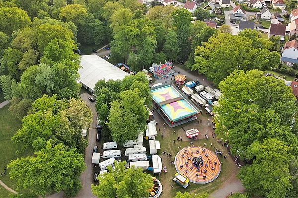 Aufnahme aus der Luft vom Festplatz im Stadtpark mit Festzelt und Fahrgeschäften.
