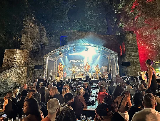 Gefüllter Festplatz in der Schlossruine während des Auftritts einer Rockband.