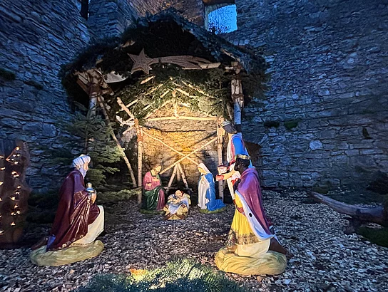 Eine festlich beleuchtete Krippe in der Schlossruine während des Weihnachtsmarkts im Stadtpark.