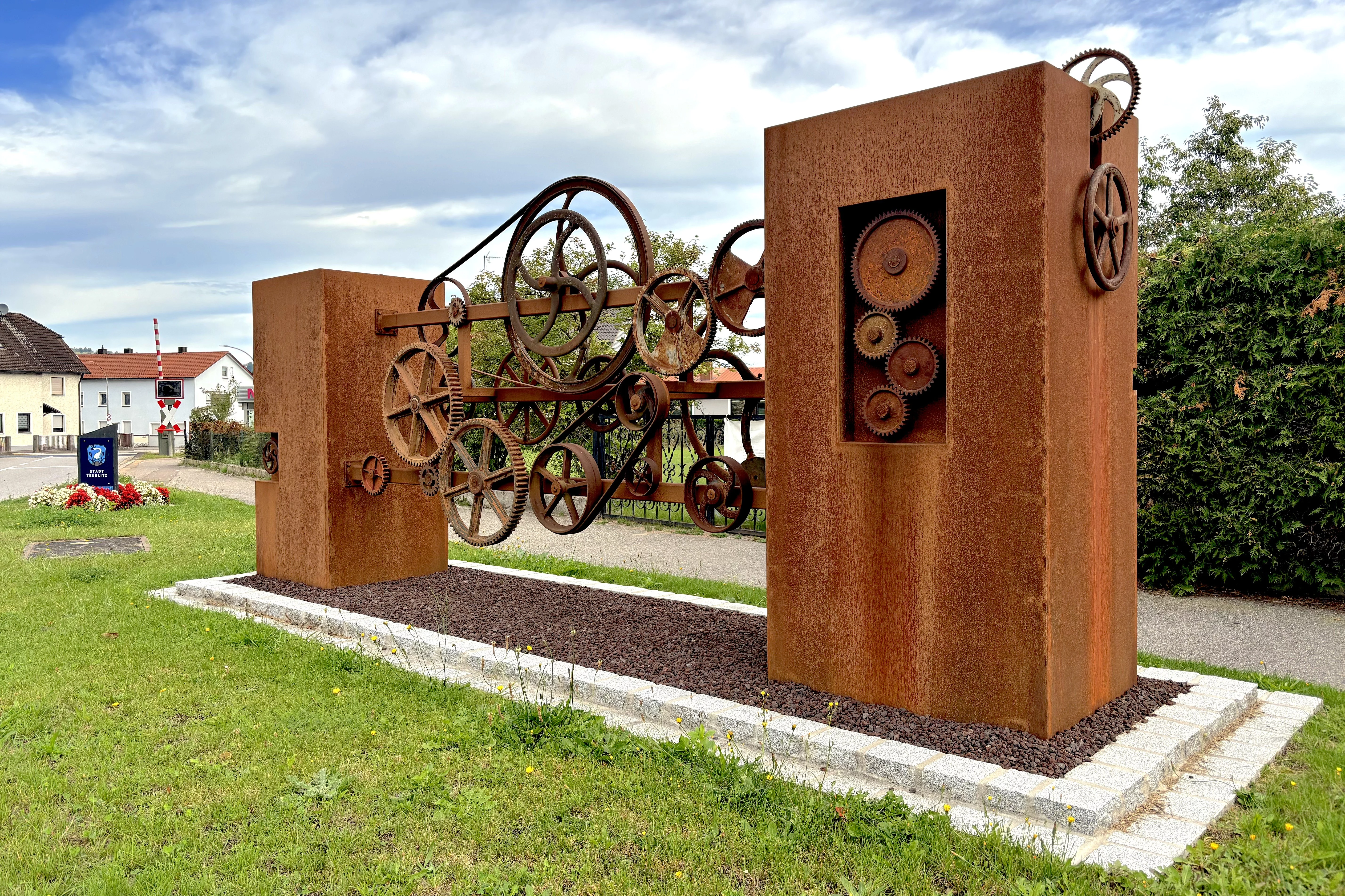 Eine verrostete Skulptur mit alten Zahnrädern und Stehlen.