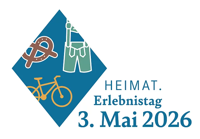 Das Bild zeigt das Logo des „Heimat.Erlebnistag“ mit Symbolen einer Brezel, Lederhose und eines Fahrrads in einem blauen, rautenförmigen Feld sowie dem Schriftzug „HEIMAT. Erlebnistag 3. Mai 2026“.