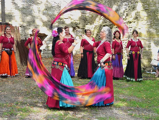 Kunstvoll gekleidete und geschminkte Tänzerinnen in Formation.