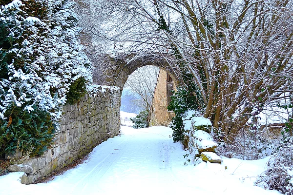 Verschneiter Weg durch einen aus Bruchsteinen errichteten Torbogen in der Schlossmauer.