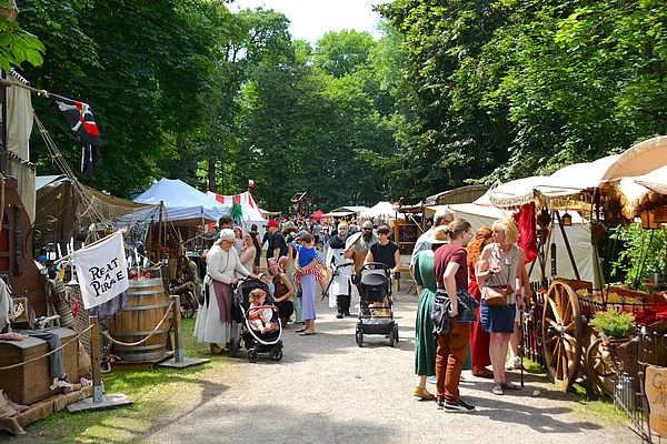 Ein Weg im Stadtpark gesäumt von Händlern, die im Umgang mit Kundinnen und Kunden sind.
