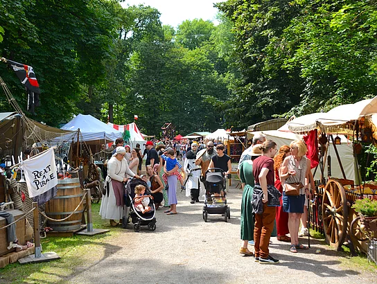 Ein Weg im Stadtpark gesäumt von Händlern, die im Umgang mit Kundinnen und Kunden sind.