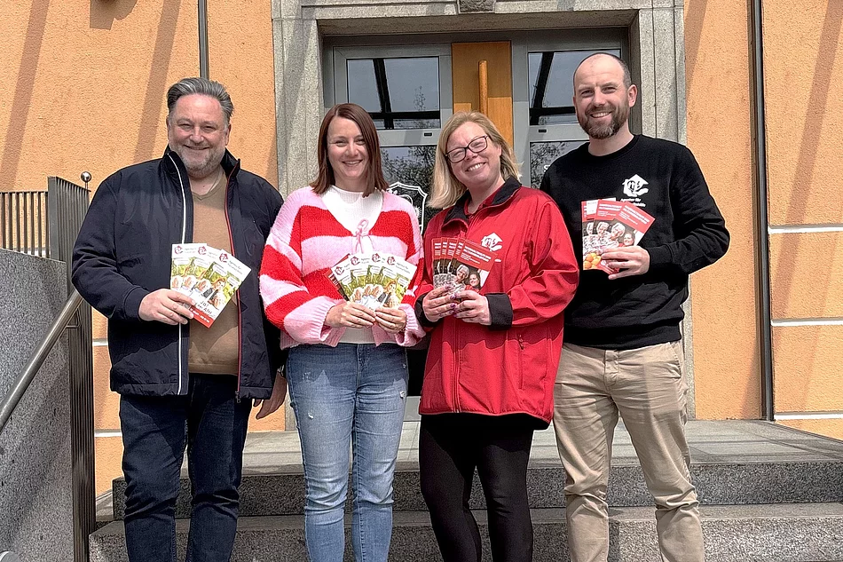 Vertreterinnen und Vertreter der Agentur für Haushaltshilfe präsentieren gemeinsam vor dem Rathaus Informationsflyer zu ihrem Unterstützungsangebot.