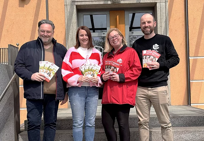 Vertreterinnen und Vertreter der Agentur für Haushaltshilfe präsentieren gemeinsam vor dem Rathaus Informationsflyer zu ihrem Unterstützungsangebot.