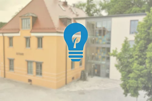 Im Vordergrund ein Glühbirnen-Icon und im Hintergrund das Rathaus Teublitz