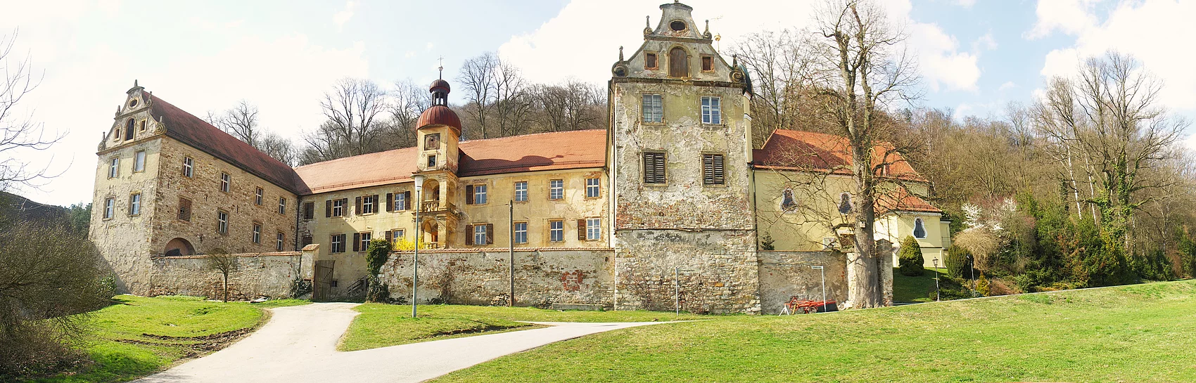Eine mit Steinmauern errichtete Schlossanlage auf einem grünen Hügel.