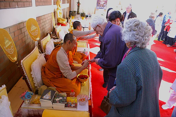 Besucherinnen und Besucher werden von den in orangen Roben gekleideten Mönchen begrüßt.