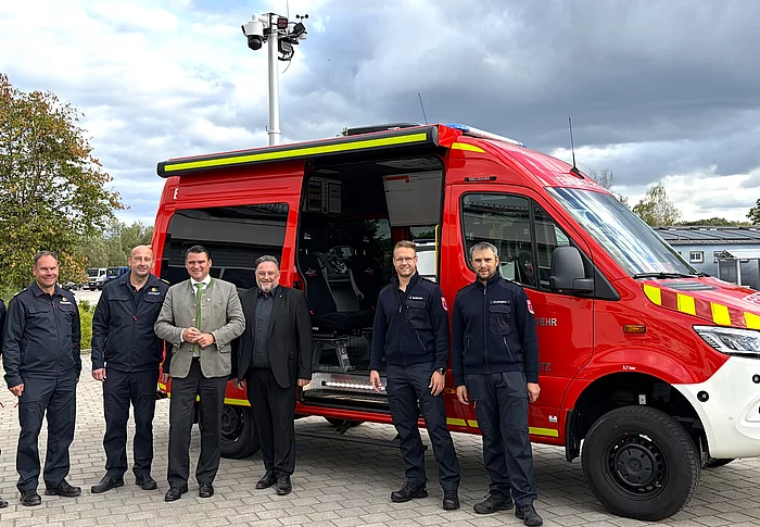 Sieben Personen aus Feuerwehr, Kreisbrandinspektion und Politik stehen für ein gemeinsames Foto vor dem geöffneten roten Einsatzleitwagen der Feuerwehr Teublitz.