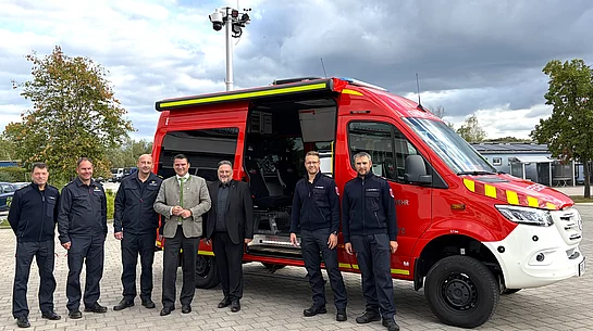 Sieben Personen aus Feuerwehr, Kreisbrandinspektion und Politik stehen für ein gemeinsames Foto vor dem geöffneten roten Einsatzleitwagen der Feuerwehr Teublitz.