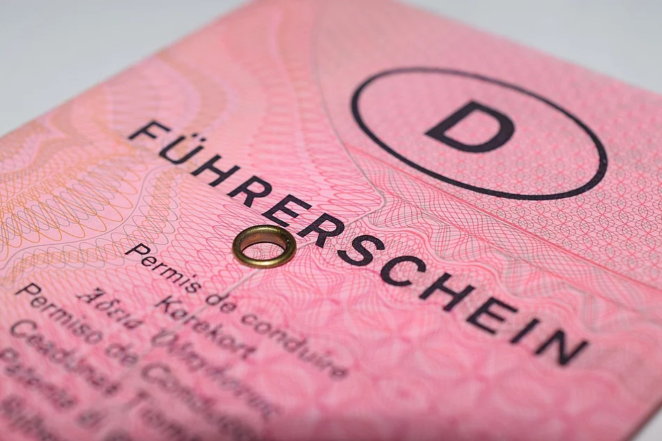 Das Bild zeigt eine Nahaufnahme des alten rosa deutschen Papierführerscheins („rosa Lappen“) mit deutlich sichtbarem Schriftzug „Führerschein“, Sicherheitsmustern und der typischen Metallöse.