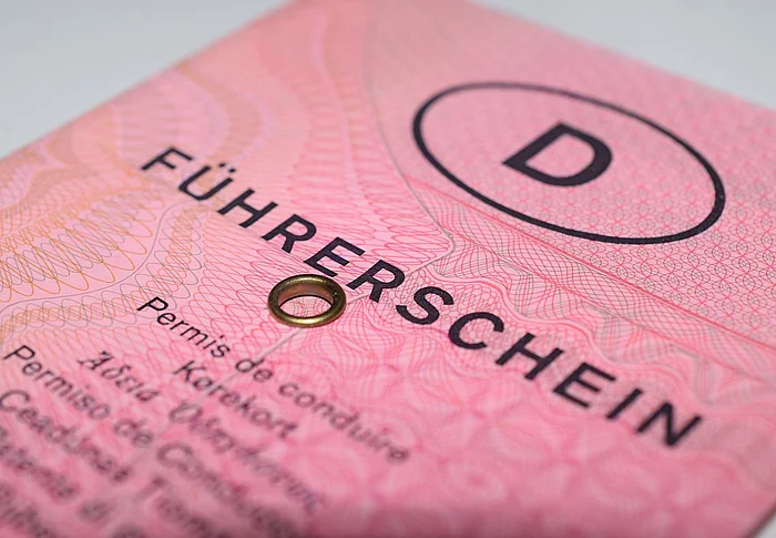 Das Bild zeigt eine Nahaufnahme des alten rosa deutschen Papierführerscheins („rosa Lappen“) mit deutlich sichtbarem Schriftzug „Führerschein“, Sicherheitsmustern und der typischen Metallöse.
