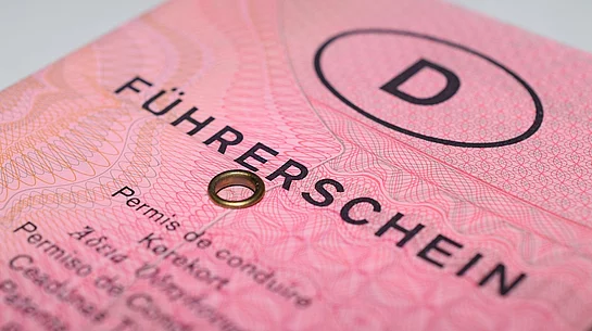 Das Bild zeigt eine Nahaufnahme des alten rosa deutschen Papierführerscheins („rosa Lappen“) mit deutlich sichtbarem Schriftzug „Führerschein“, Sicherheitsmustern und der typischen Metallöse.