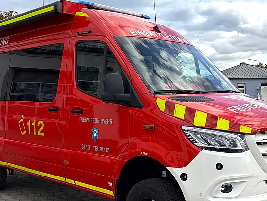 Ein roter Einsatzleitwagen der Freiwilligen Feuerwehr Teublitz steht mit gelben Warnmarkierungen und weißer Front vor dem Feuerwehrgerätehaus.