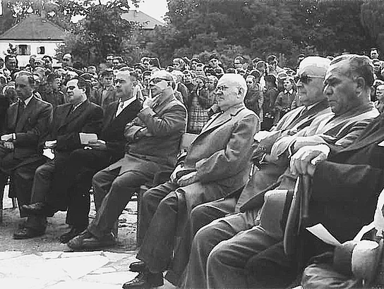 Schwarz-Weiß-Aufnahme der Einweihungsfeier des Teublitzer Schulhaus-Erweiterungsbaus im Jahr 1957. In der ersten Reihe sitzen mehrere Ehrengäste, dahinter verfolgen zahlreiche Erwachsene und Kinder die Feier.