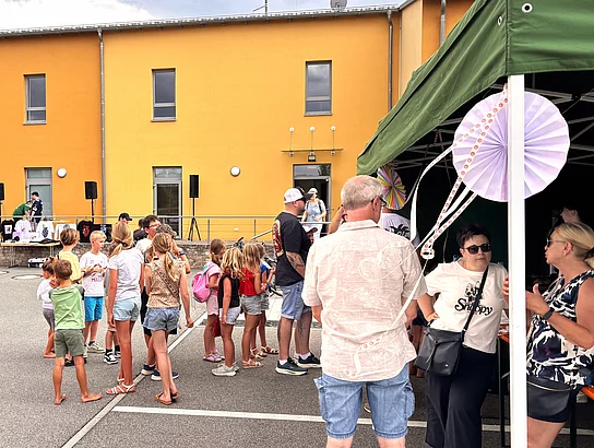 Kinder und Erwachsene stehen vor einem Pavillon mit Mitmachangeboten und genießen das bunte Programm auf dem Gelände des Mehrgenerationenhauses.
