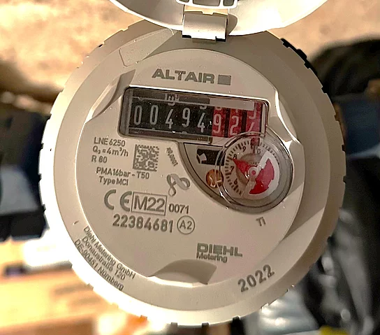 Nahaufnahme eines Wasserzählers, dessen Ziffernstand deutlich ablesbar ist und von technischen Angaben auf dem Gehäuse umgeben wird.