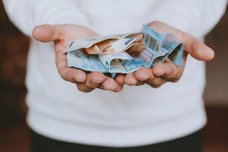 Aufgeschlagene Hände eines Mannes auf dem Bargeld liegt, das symbolisch gereicht werden.