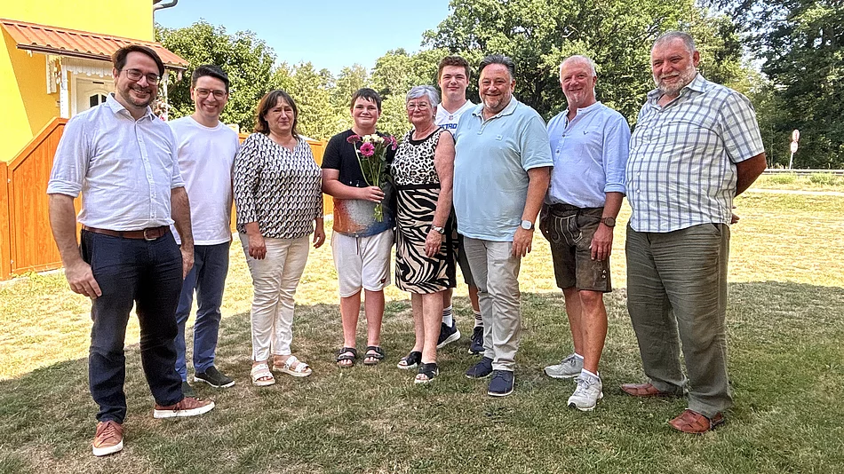 Bürgermeister Thomas Beer steht gemeinsam mit der Jubilarin Romy Hermann-Reisinger sowie mehreren Familienangehörigen und Wegbegleitern im Garten für ein Erinnerungsfoto anlässlich ihres 70. Geburtstags.