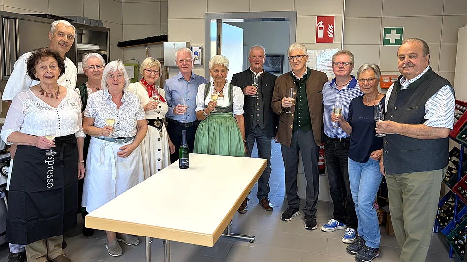 Die Mitglieder des Seniorenbeirats stehen vor Beginn des Oktoberfests gemeinsam in der Küche des Mehrgenerationenhauses und halten zum Teil Gläser zum Anstoßen in den Händen.