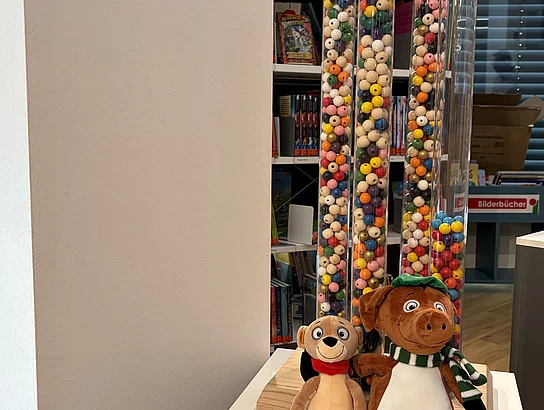 Mehrere durchsichtige Säulen sind mit bunten Perlen gefüllt, wobei jede Perle für ein während des Sommerferien-Leseclubs gelesenes Buch steht.