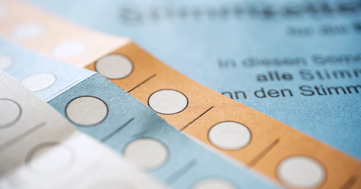 Übereinander liegende Stimmzettel in weiß, blau und orange.