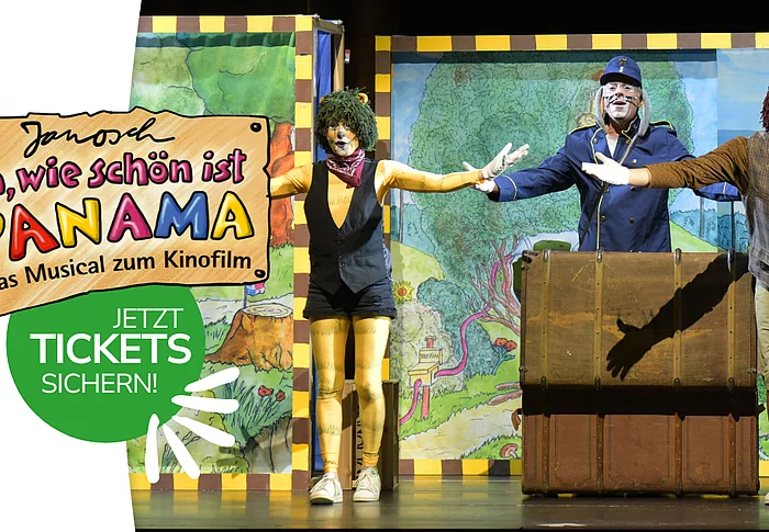 Auf dem Bild stehen drei verkleidete Schauspielerinnen und Schauspieler auf einer bunten Theaterbühne, breiten die Arme aus und spielen vor gemalten Kulissen eine fröhliche Szene aus dem Musical „Oh, wie schön ist Panama“.