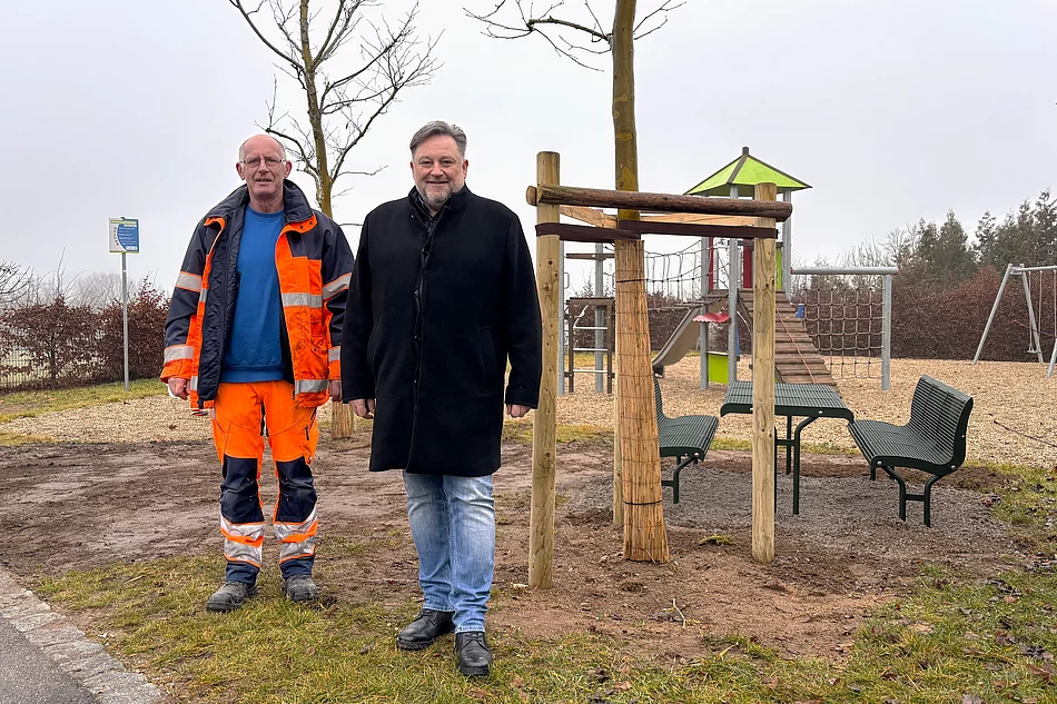 Vor dem neu aufgestellten Sitzbereich am Spielplatz Steinbruchäcker stehen ein Mitarbeiter des Bauhofs und der Erste Bürgermeister gemeinsam für ein Foto.