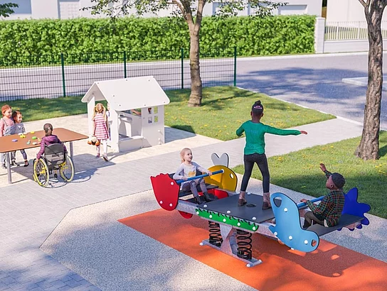 Mehrere Kinder spielen gemeinsam auf einer barrierefreien Wippe und an einem Tisch, während im Hintergrund ein kleines Spielhaus steht und auch ein Kind im Rollstuhl beteiligt ist.