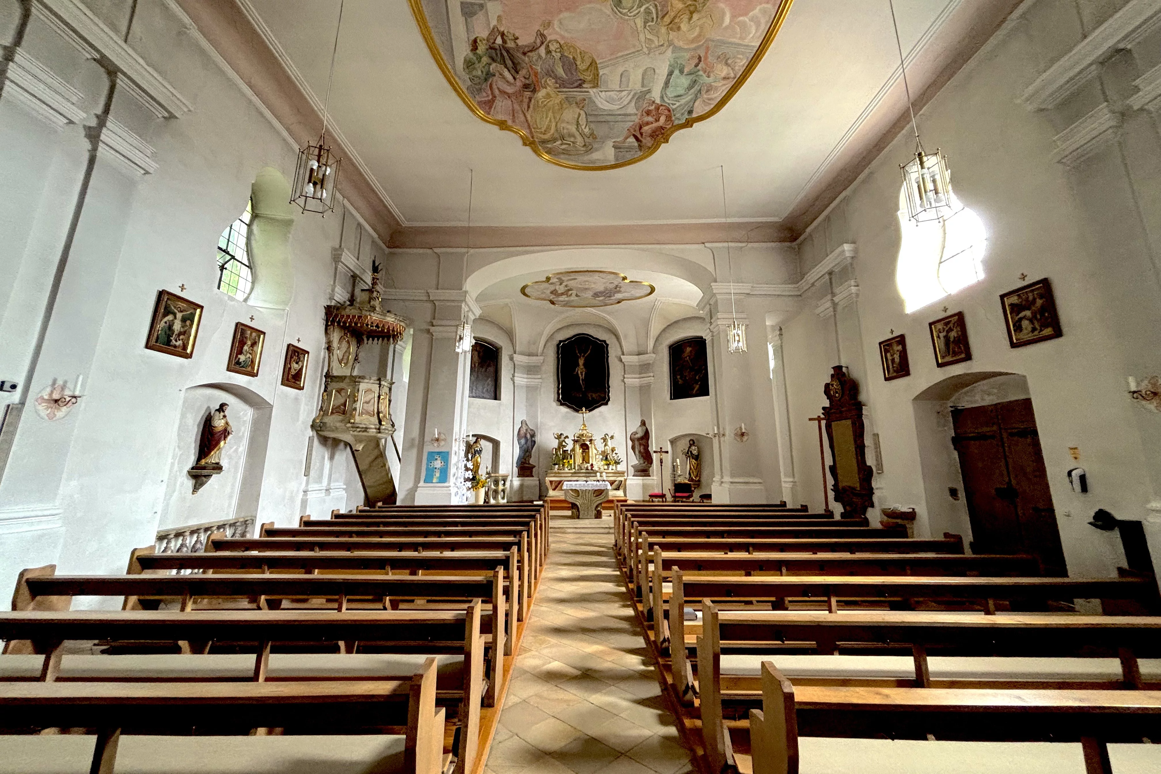 Blick durch einen prunkvollen Innenraum einer kleinen Kirche in Richtung Altar.
