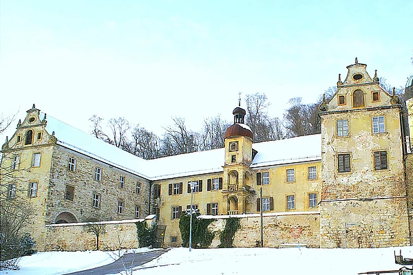 Eine mit Steinmauern errichtete Schlossanlage auf einem mit Schnee bedecktem Hügel.