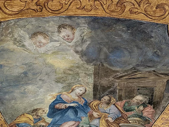 Detailaufnahme eines historischen Deckengemäldes in der Marien-Wallfahrtskirche Saltendorf. Das von einem ornamentierten goldbraunen Rahmen eingefasste Bild zeigt eine religiöse Szene mit mehreren Personen, darunter eine zentral sitzende Frau in blauem Gewand. Oberhalb der Gruppe sind zwei Engel dargestellt.