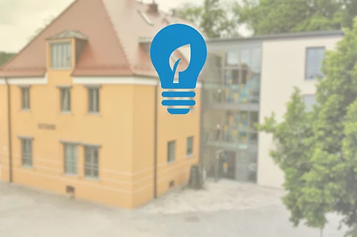 Im Vordergrund ein Glühbirnen-Icon und im Hintergrund das Rathaus Teublitz