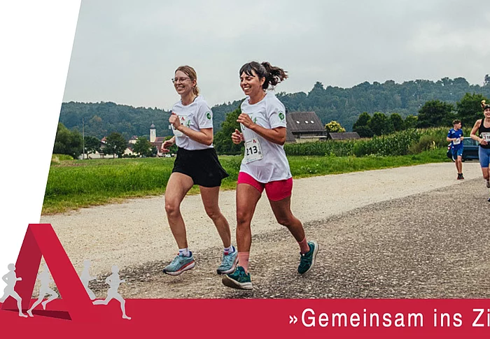 Mehrere Läuferinnen und Läufer nehmen auf einer Strecke durch die Natur am Städtedreieckslauf teil und laufen gemeinsam ihrem Ziel entgegen.