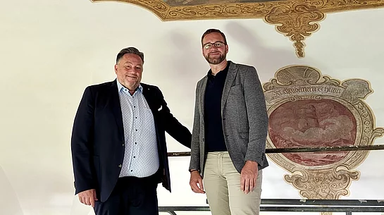 Bürgermeister Thomas Beer und Pfarrer Lucas Lobmeier stehen auf dem Arbeitsgerüst unmittelbar unter einem restaurierten Deckengemälde der Marien-Wallfahrtskirche Saltendorf. Im Hintergrund ist ein weiteres historisches Wandmotiv zu sehen.