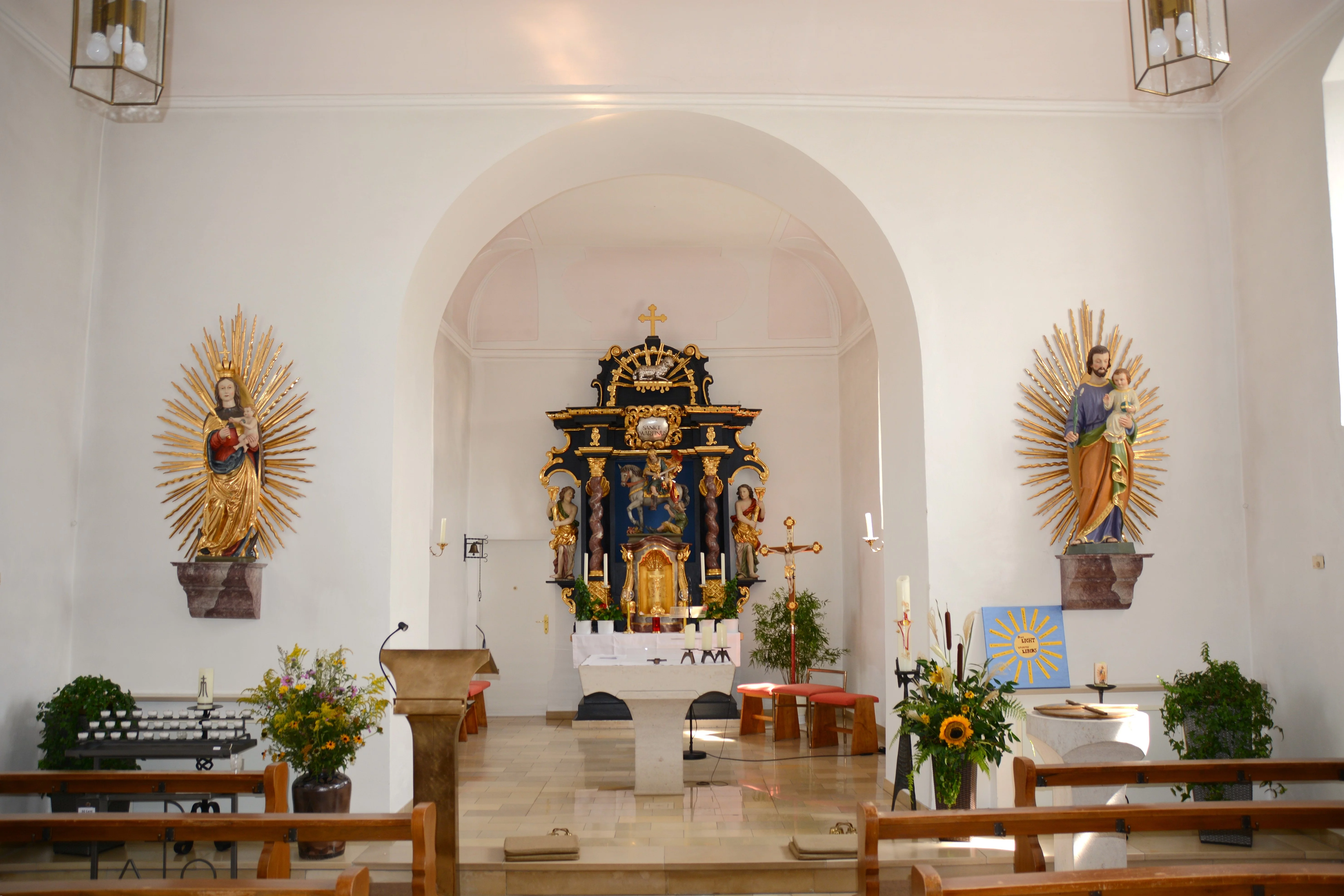 Ansicht des Altars im Innenraum mit prunkvollen Statuen, ansonsten wenig Einrichtung.
