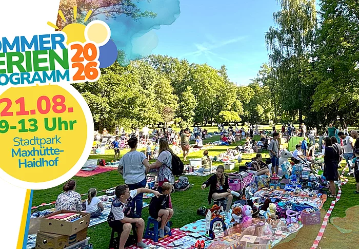 Eine weitläufige Parkanlage an einem sonnigen Tag, auf deren großen Rasenflächen zahlreiche Familien ihre Decken und Verkaufsstände aufgebaut haben. Kinder und Erwachsene stöbern zwischen Spielzeug, Büchern, Kleidung und weiteren Secondhand-Artikeln. Hohe, schattenspendende Bäume umrahmen das Gelände und verleihen dem Flohmarkt eine lebendige, zugleich entspannte Atmosphäre.