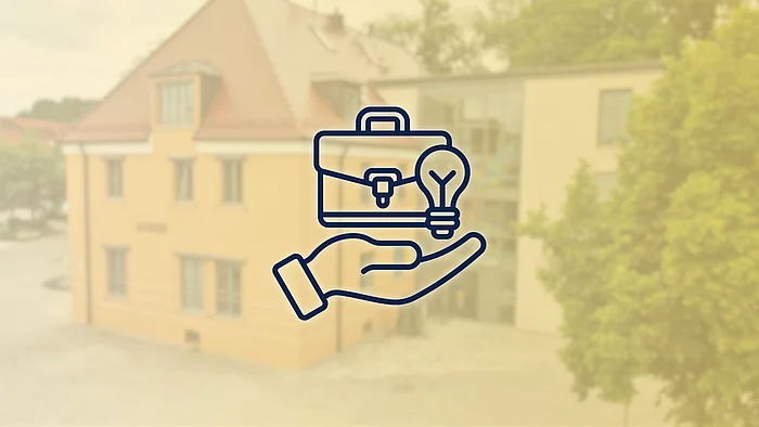 Grafik zum Thema Stellenangebote. Vor einem unscharf dargestellten Verwaltungsgebäude ist ein dunkelblaues Symbol zu sehen: Eine geöffnete Hand trägt einen Aktenkoffer und eine Glühbirne. Die Darstellung symbolisiert berufliche Möglichkeiten, Arbeit und neue Ideen.