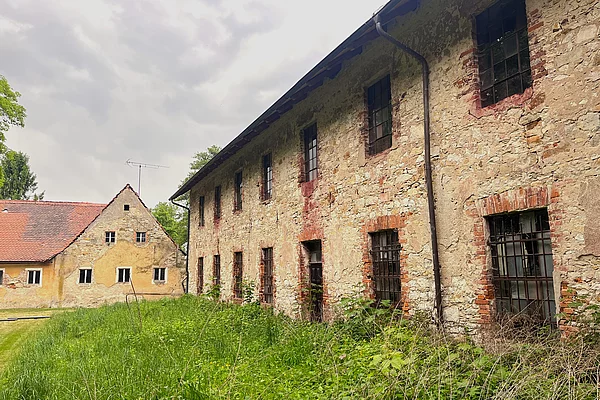 Ein sehr altes Gebäude aus Steinen erbaut, umgeben von saftig grünen Wiesen.