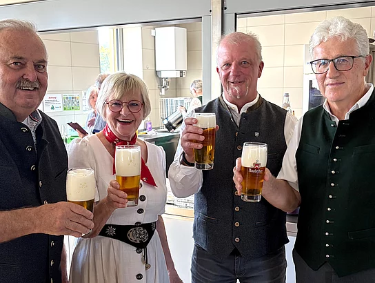 Vier Mitglieder des Seniorenbeirats stehen nach dem Fassanstich gemeinsam neben dem Bierfass und halten gefüllte Biergläser in den Händen.