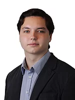 Ein junger Mann mit ordentlich frisiertem Haar trägt ein Hemd und ein Sakko und blickt neutral vor hellem Hintergrund in die Kamera.