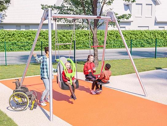 Drei Kinder schaukeln gemeinsam auf einer barrierefreien Schaukelanlage, während daneben ein Rollstuhl steht und andere Kinder im Hintergrund spielen.